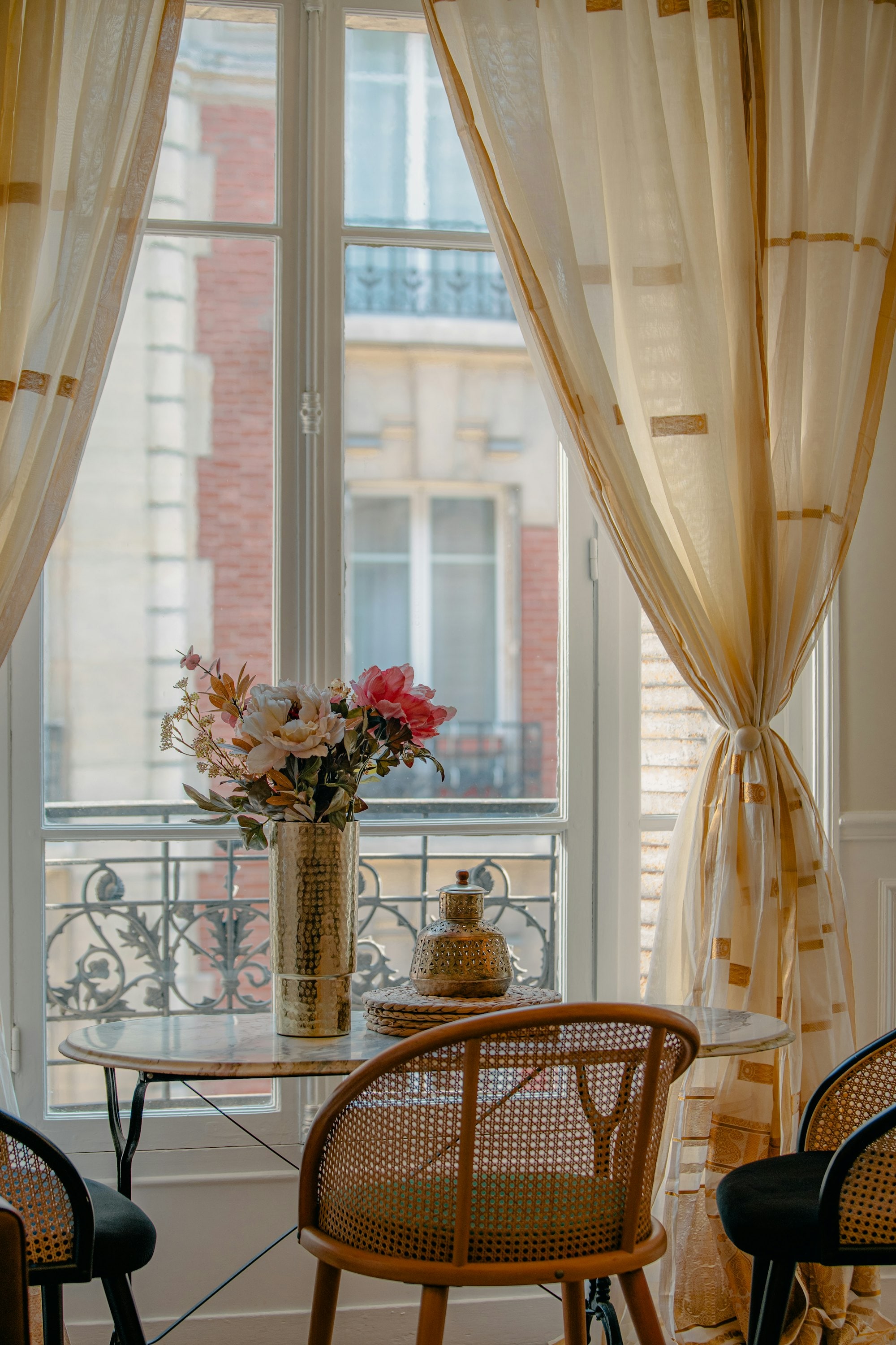 Table dressée devant une fenêtre ouverte, lumière du matin dans un appartement parisien